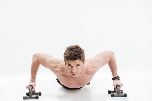 Free photo young fit sportsman doing push ups with bars