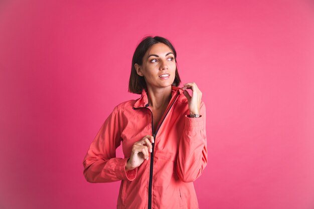 Молодая женщина в спортивной куртке на розовом