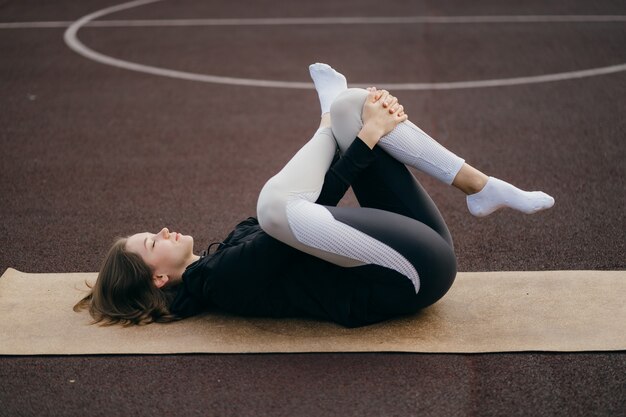 スポーツウェアの若いフィットの女性は、遊び場で屋外でトレーニングします。