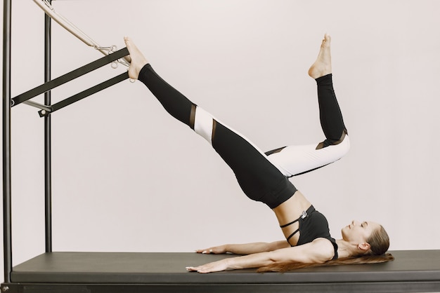 Young fit woman training in gym. Woman wearing black sportwear. Caucasian girl stretching with equipment.