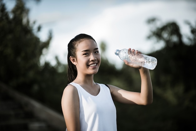 運動をした後に水のボトルを保持している若いフィットネス女性の手