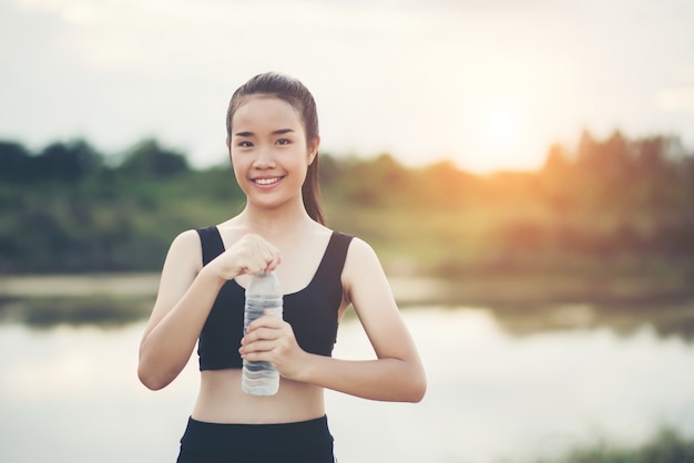 運動をした後に水のボトルを保持している若いフィットネス女性の手