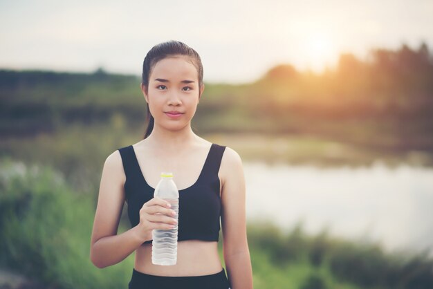 運動をした後に水のボトルを保持している若いフィットネス女性の手