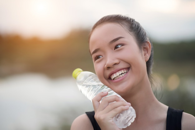 運動をした後に水のボトルを保持している若いフィットネス女性の手