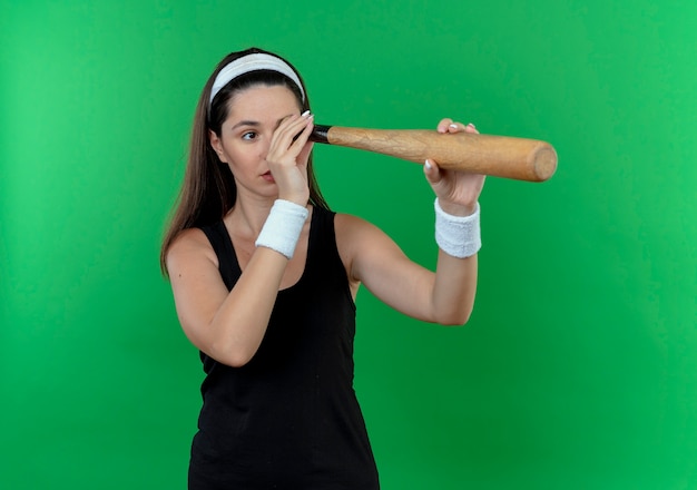 Free photo young fitness woman in headband standing over green background