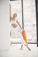 young fitness woman ready for workout holding orange yoga mat