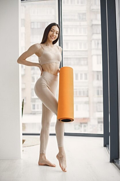Молодая фитнес-женщина готова к тренировке с оранжевым ковриком для йоги
