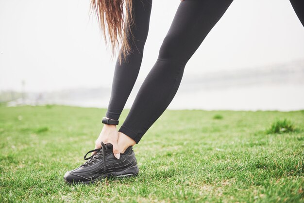 公園で実行する前に足を伸ばして若いフィットネス女性ランナー