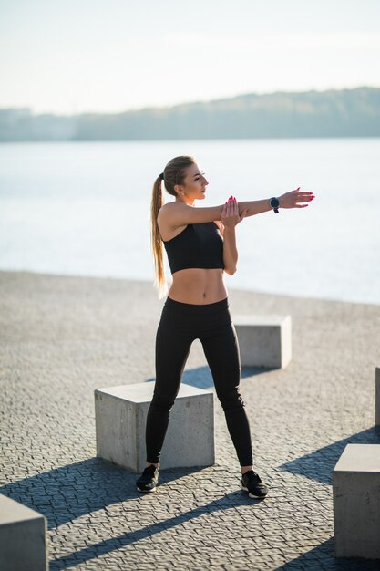 走る前に足を伸ばす若いフィットネス女性ランナー