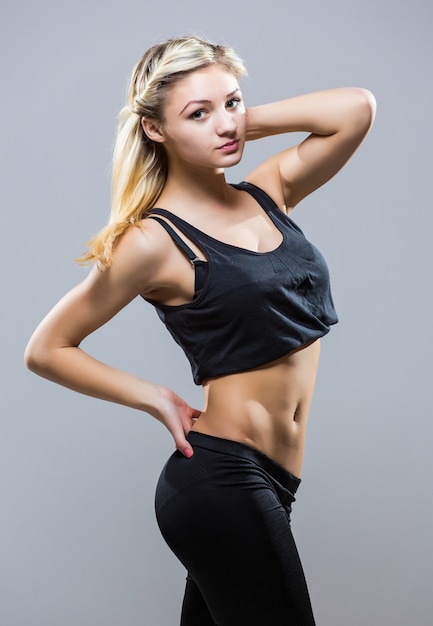 Молодая женщина фитнеса в спортивном стиле стоя на белом фоне. изолированные