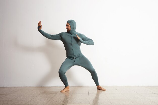 young and fitted bearded athlete male wearing his winter snowboardint baselayer thermal suite and having fun acting like a ninja