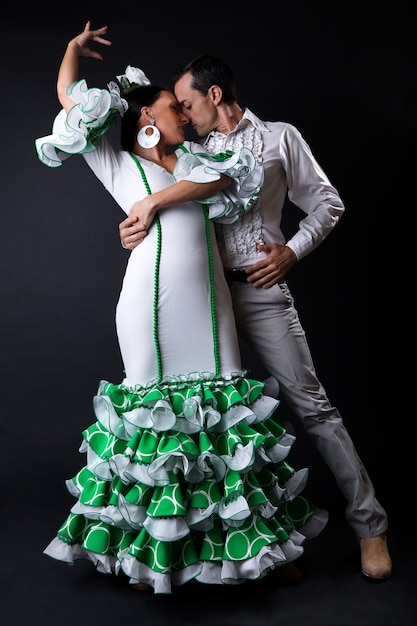 Young flamenco dancers in beautiful dress on black background.