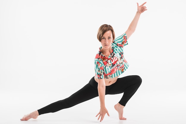 Young flexible female dancer dancing against white background