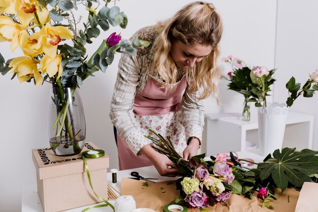 Young florist wrapping bouquet
