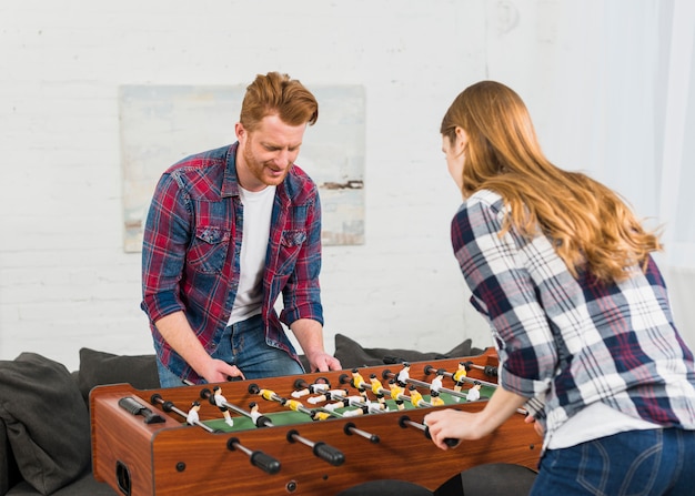 Young focused couple having fun with table soccer game