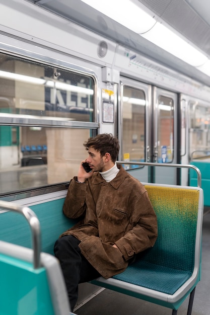 地下鉄の電車に乗ってスマートフォンで話している若いフランス人