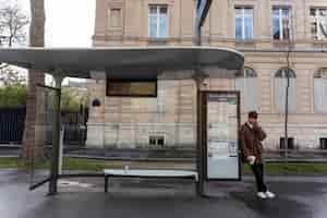 Foto gratuita giovane francese che aspetta alla stazione l'autobus e parla sullo smartphone