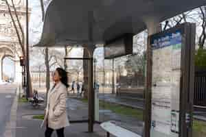 무료 사진 버스를 타기 위해 역에서 기다리는 젊은 프랑스 여성