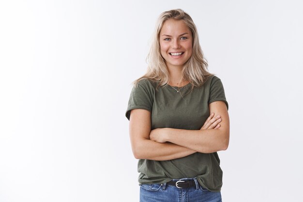 Young friendly-looking attractive mother talking other moms during b-day party crossing arms over body and smiling pleasantly at camera having fun amusing talk, posing against white background