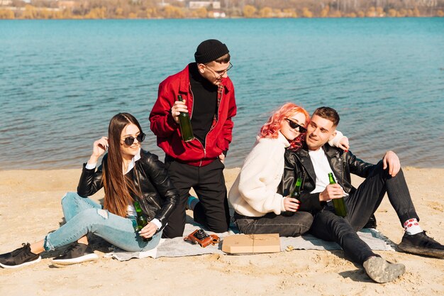 Young friends drinking beer on sunny spring beach