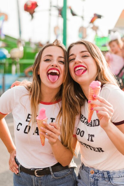 Young friends eating ice cream in the amusement park