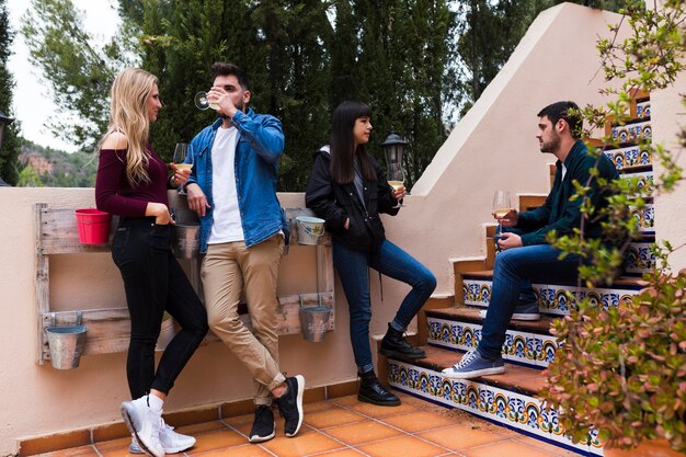 Young friends having drinks while sitting on staircase