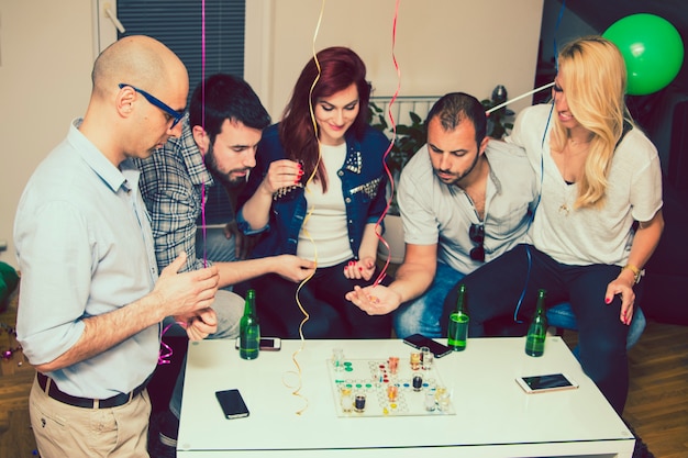 Young friends having fu at party with boardgames