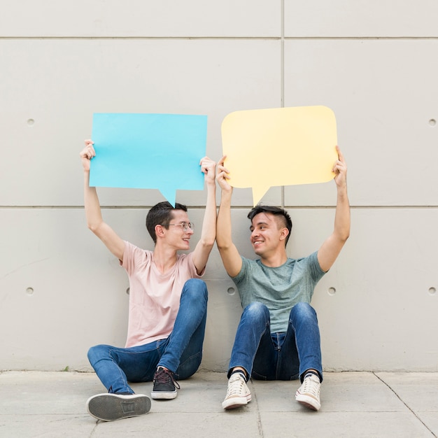 Free photo young friends holding colorful speech bubbles