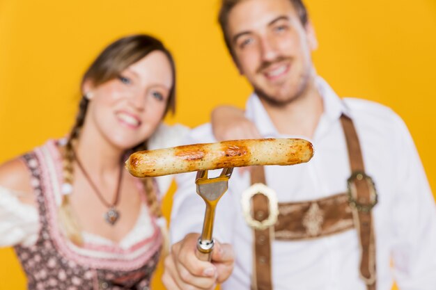 Young friends holding grilled sausage