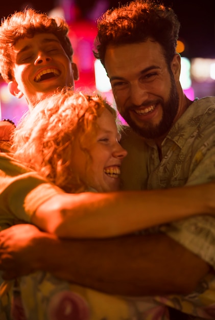 Young friends hug at night funfair