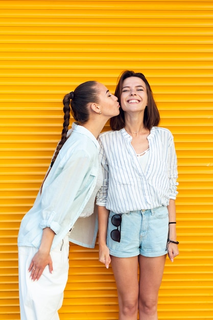 Young friends kissing her friend on the cheek 