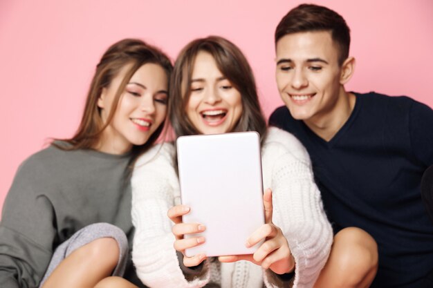 Young friends making selfie on tablet on pink