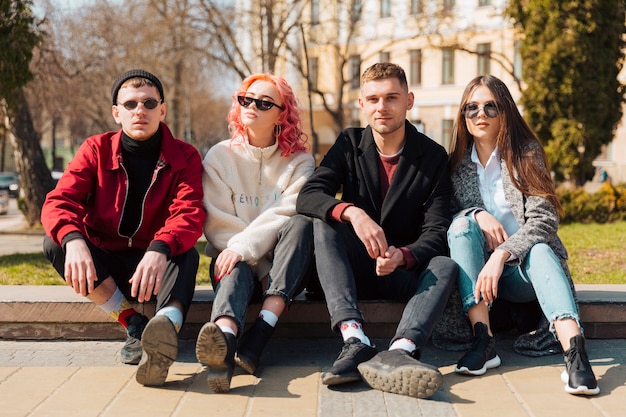 Young friends sitting on curb in city