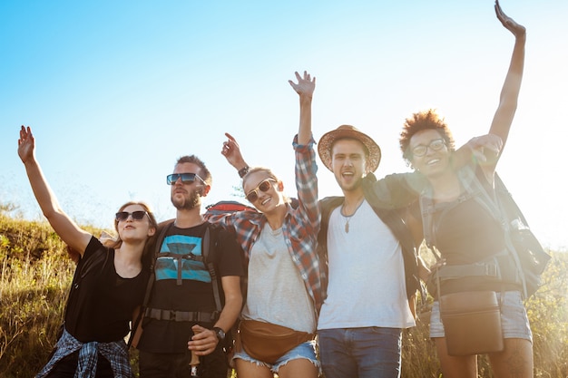 Free photo young friends smiling, rejoicing, looking at camera, standing in field