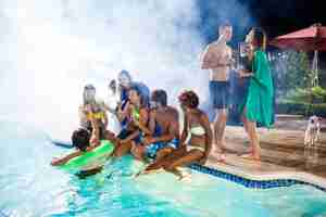 Free photo young friends smiling, rejoicing, resting at party near swimming pool