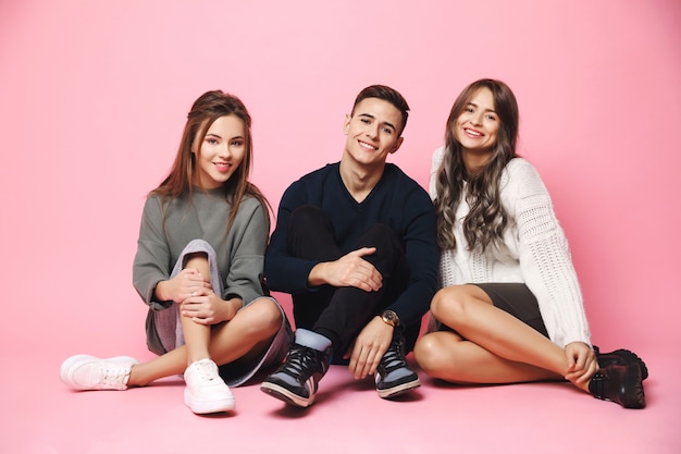 Young friends smiling sitting on pink floor