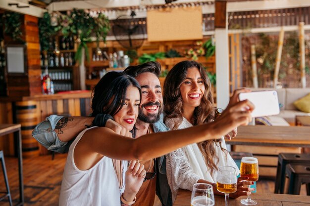 young friends taking selfie in bar