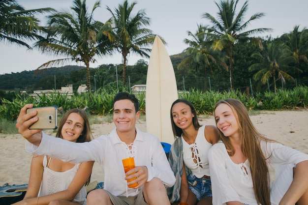 Giovani amici che prendono selfie alla festa sulla spiaggia