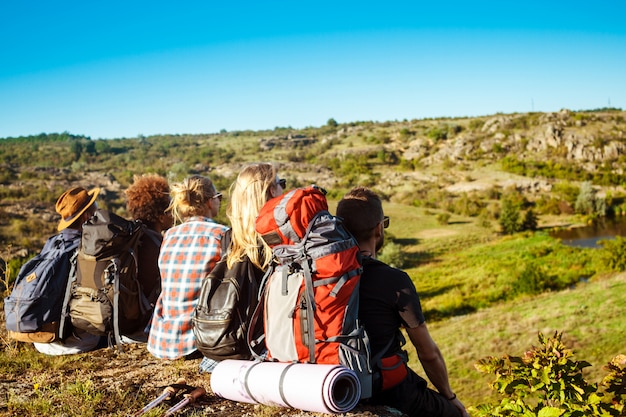 Free photo young friends travelers sitting on rock in canyon, enjoying view