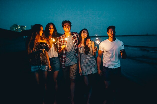 Молодые друзья с зажигалки на ночном пляже