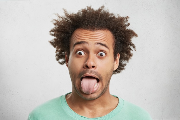 Free photo young funny afro american man looks surprisely, makes grimace