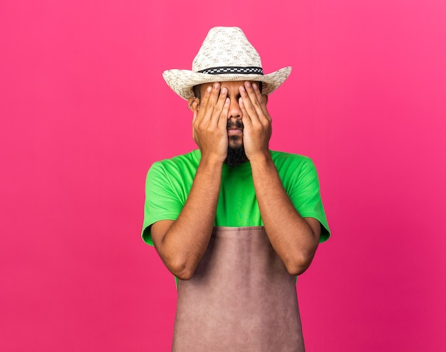 Il giovane giardiniere afroamericano che indossa un cappello da giardinaggio ha coperto il viso con le mani