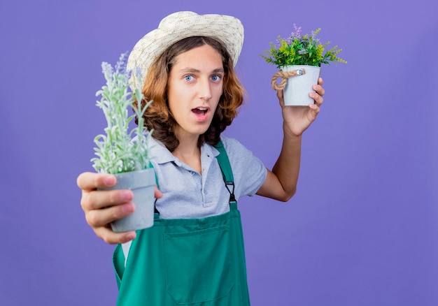 無料写真 つなぎ服と帽子をかぶって鉢植えの植物の笑顔を示す若い庭師の男