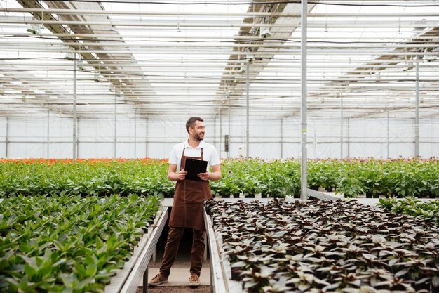 Young gardener working with plants in greenhouse