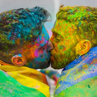 Young gays kissing on holi color festival