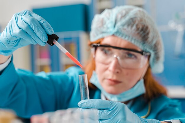 Young ginger woman chemist using samples