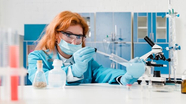 Молодой химик женщины имбиря работая в ее лаборатории