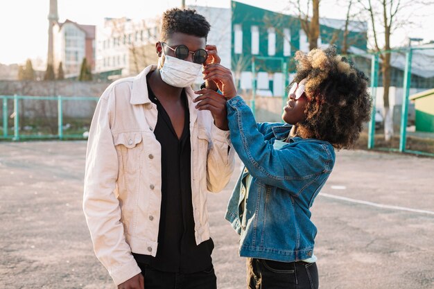 Young girl arranging medical mask of friend