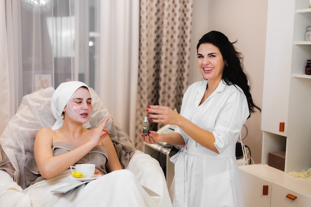 A young girl in a beauty salon in a cosmetology office lies on the bed relaxes with a mask on her face