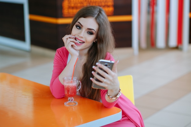 Young girl biting her finger while looking at her smartphone